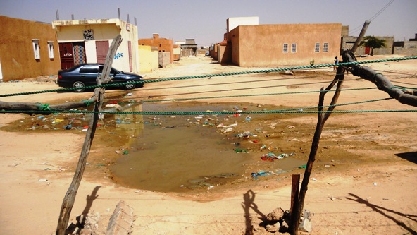مستنقع آخر يقع أمام محل لتنظيف الثياب، يبذل العامل فيه جهده لإقناع الناس أن مصدر المستنقع هو عطب الأنبوب وليس مصدرها محله (الأخبار)
