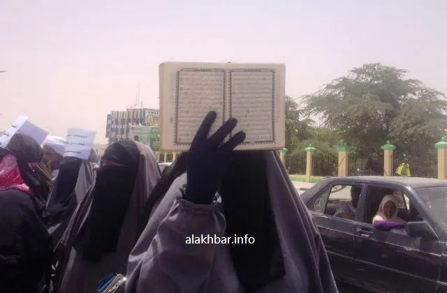 إحدى المحتجات وهي ترفع مصحفا خلال مسيرة اليوم من القصر الرئاسي إلى و?