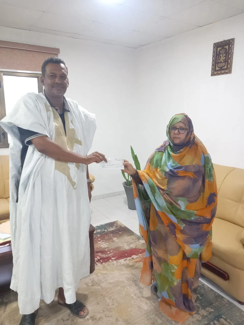 جانب من تسليم المديرة المالية بالمنياء شيك مالي لممثل أسر الضحايا/ ا?
